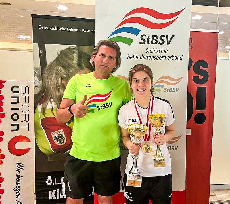 Das Foto zeigt den Sportdirektor des Steirischen Behindertensportverbandes herbert Sidak und die Sportlerin Sarah-Maria Baumegger. Sidak zeigt einen Daumen hoch, Baumegger hält zwei Pokale in den Händen. 